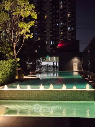 Luxurious night view of a modern apartment building with illuminated swimming pool.