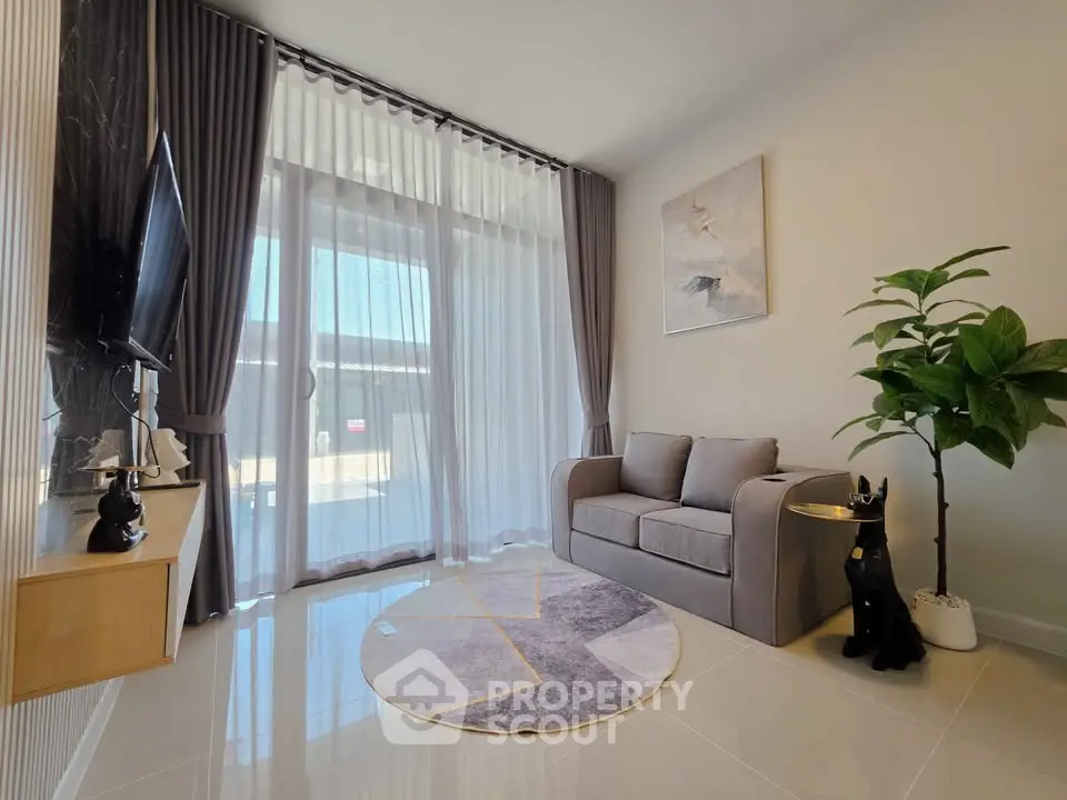 Modern living room with large window, stylish decor, and cozy seating area.