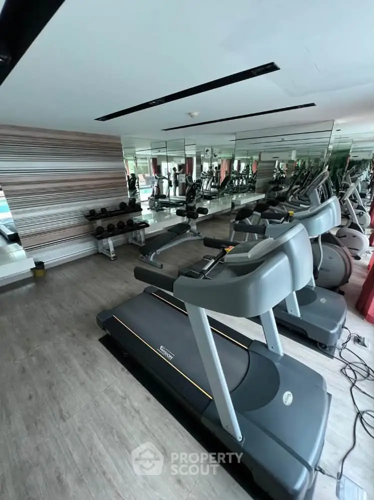 Modern gym with treadmills and weights in a stylish residential building.