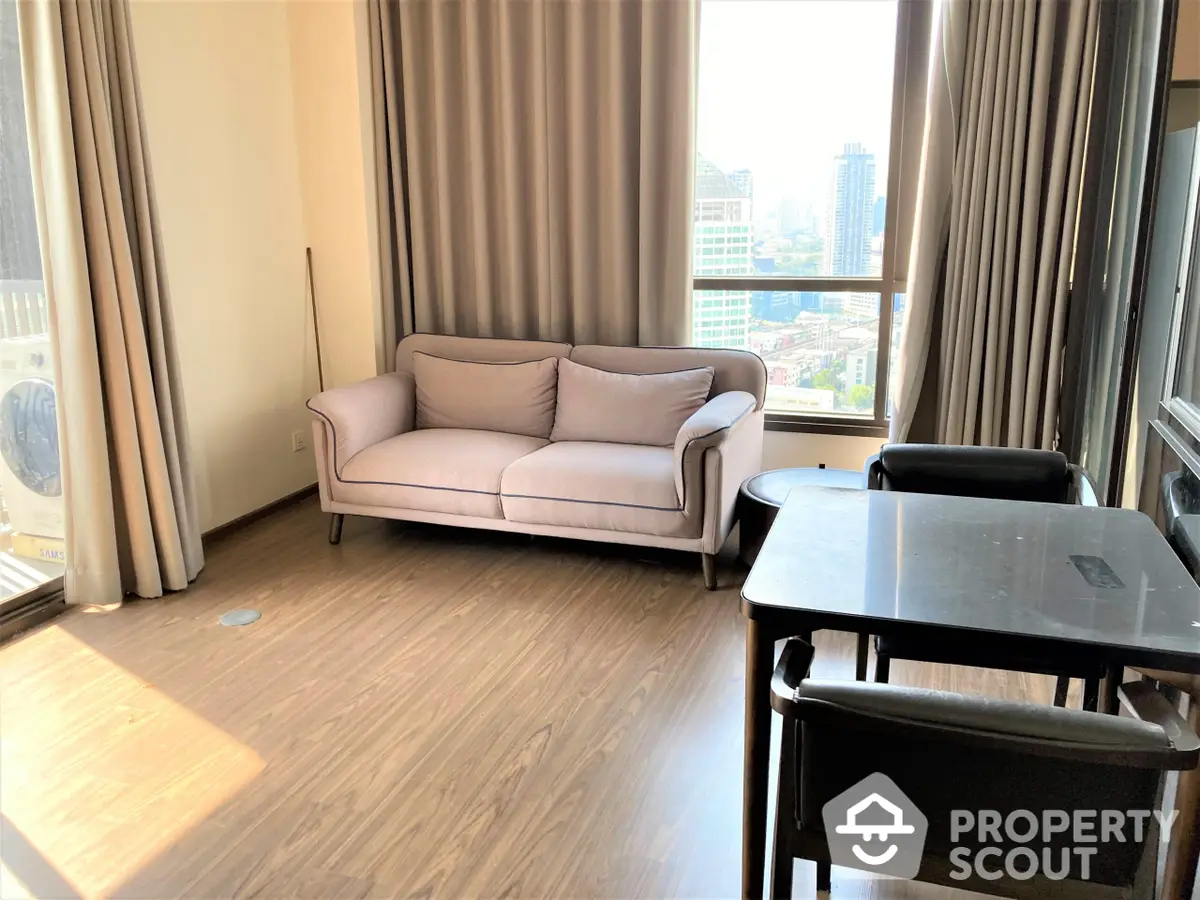 Sunlit high-rise living room with elegant pink sofa and modern dining set, boasting expansive windows offering a city view.