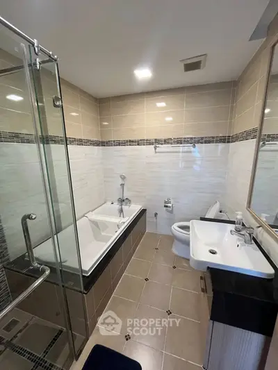Modern bathroom with glass shower and bathtub in elegant tile design