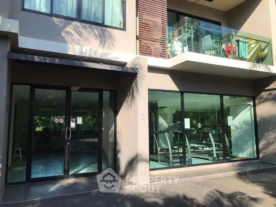 Modern building exterior with gym and balcony, showcasing sleek design and fitness amenities.