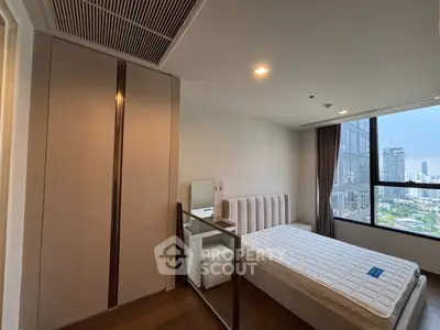 Modern bedroom with city view, featuring a sleek wardrobe and comfortable bed in a high-rise apartment.