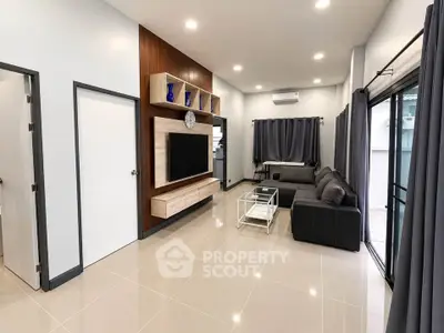 Modern living room with sleek design, featuring a large TV, stylish furniture, and elegant decor.