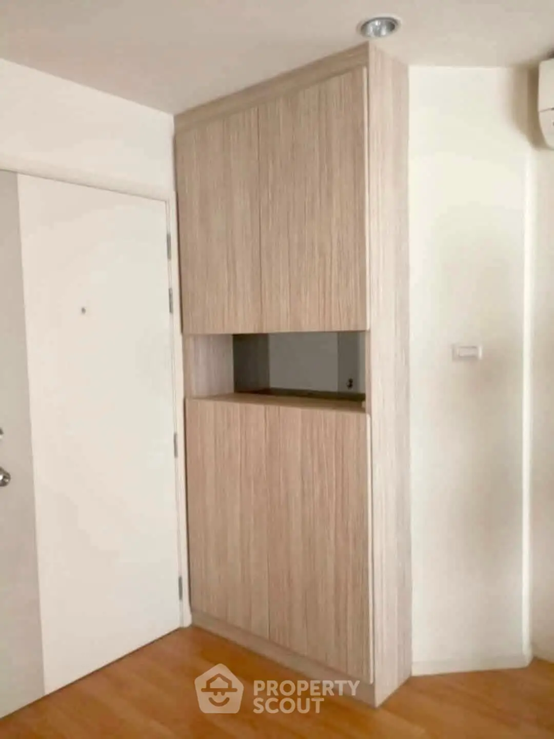 Modern minimalist storage cabinet in a bright interior space with wooden flooring.