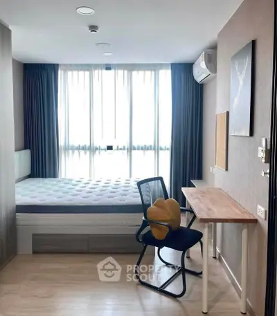 Modern bedroom with large window, stylish desk, and comfortable chair in a bright apartment.