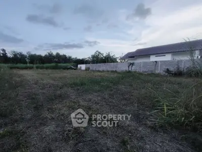 Spacious plot of land with lush greenery and a view of a modern house, perfect for building your dream home.