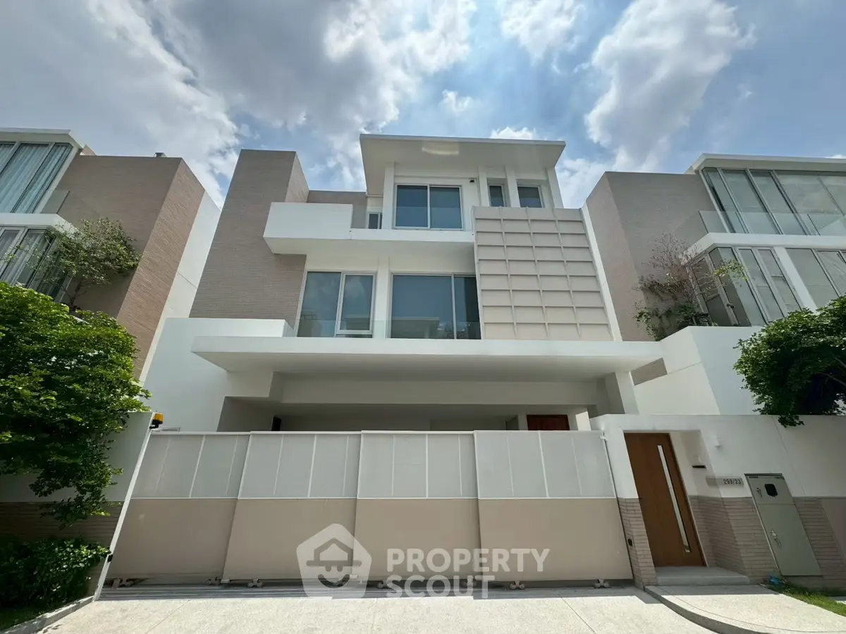 Modern multi-story residential building with sleek design and large windows under a partly cloudy sky.