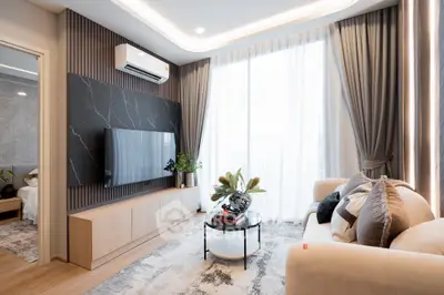 Modern living room with elegant decor and large windows, featuring a sleek TV setup and cozy seating area.