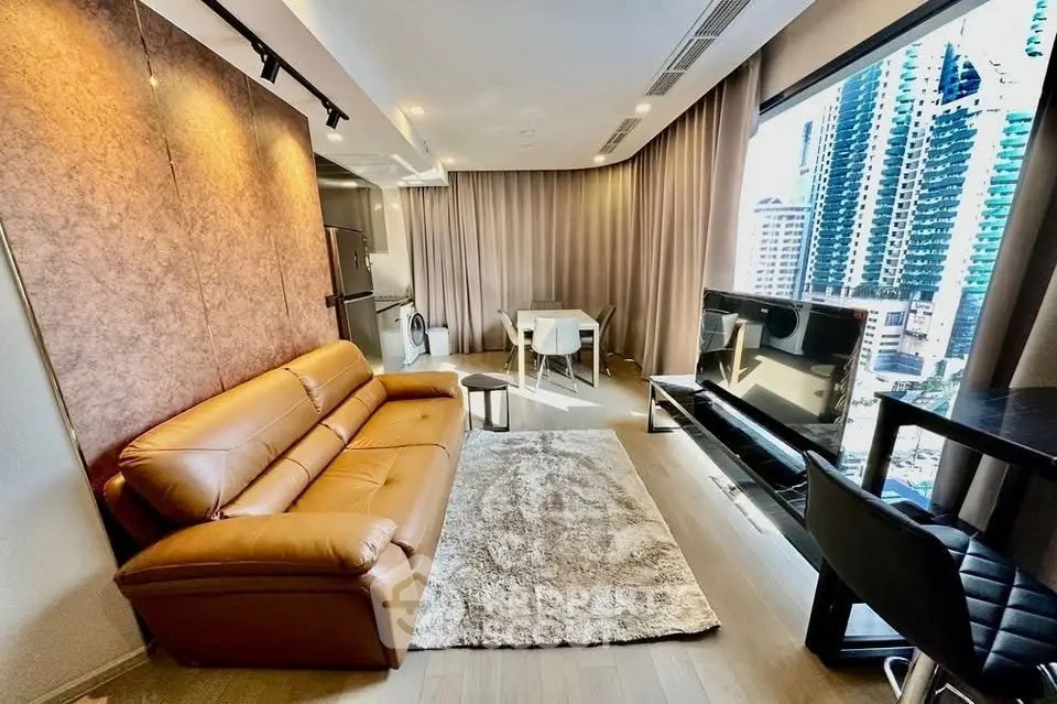 Modern living room with city view, leather sofa, and stylish decor in high-rise apartment.