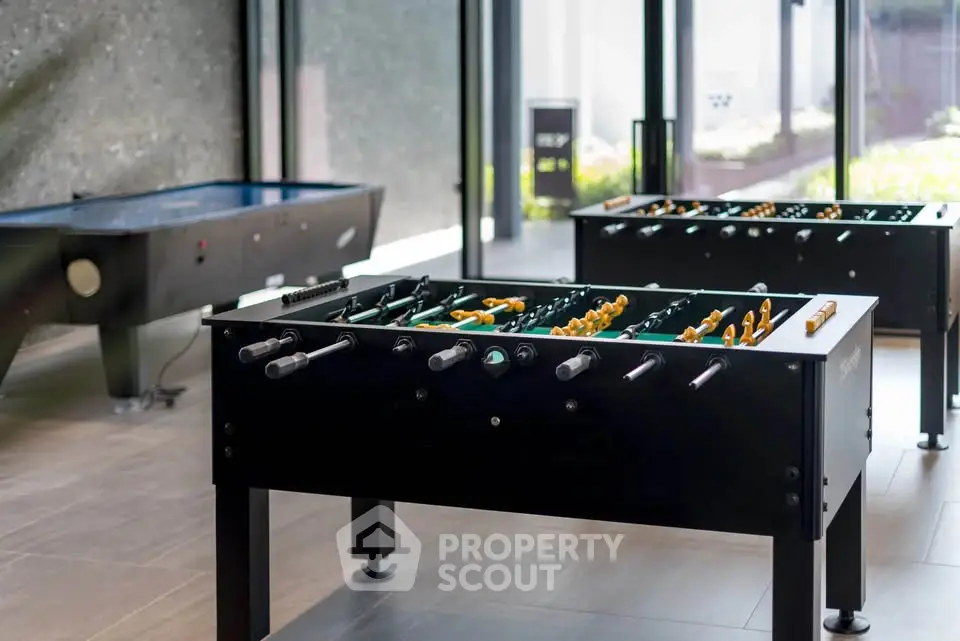 Modern game room with foosball and air hockey tables in a luxury apartment complex.