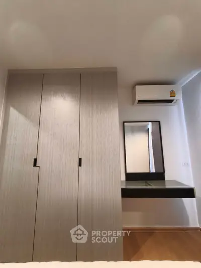 Modern bedroom with sleek wardrobe and air conditioning unit, perfect for comfortable living.