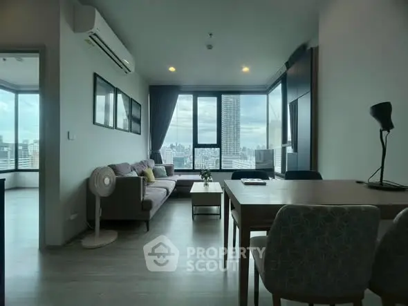 Modern living room with city view, featuring stylish furniture and large windows for natural light.