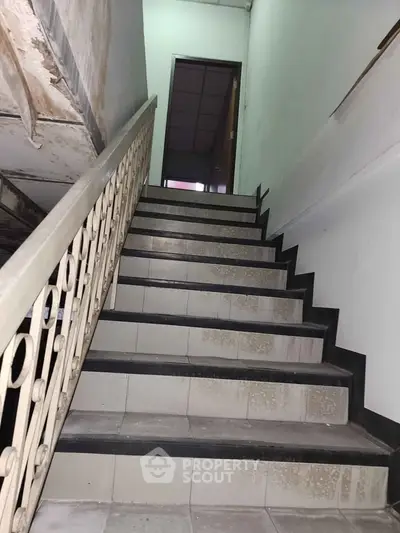 Staircase in a residential building with tiled steps and metal railing.