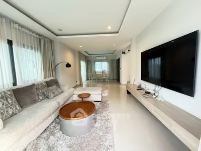 Spacious modern living room with elegant decor and large TV, perfect for relaxation and entertainment.