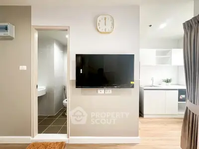 Modern apartment interior with wall-mounted TV and sleek kitchen design