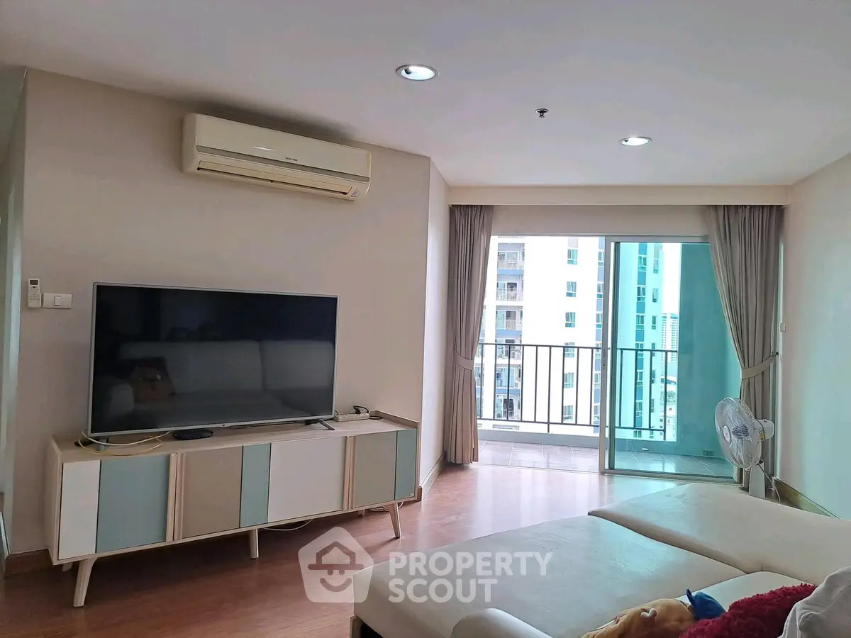 Spacious living room with modern decor and balcony view in a high-rise apartment.