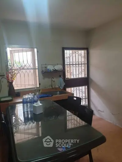Cozy kitchen with glass table and natural light, ideal for intimate gatherings.