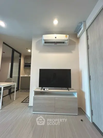 Modern living room with sleek TV setup and air conditioning in a stylish apartment.