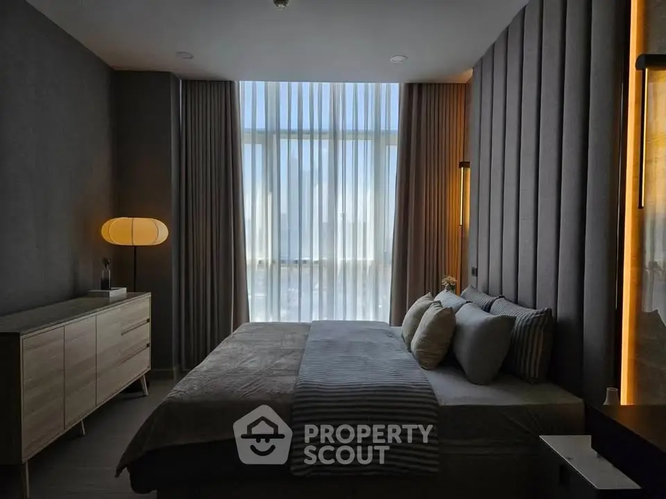 Luxurious bedroom with modern decor and floor-to-ceiling windows offering stunning views.