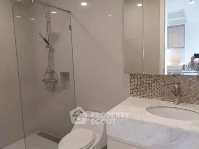 Modern bathroom with glass shower and marble countertop in luxury apartment.