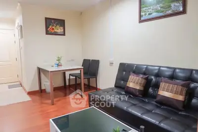 Cozy living room with black leather sofa and dining area in modern apartment.