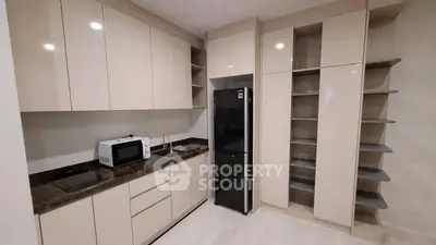 Modern kitchen with sleek cabinetry and appliances, featuring a microwave and refrigerator.