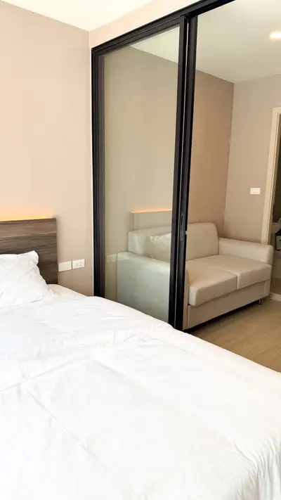 Modern bedroom with sliding glass doors and cozy sofa, perfect for urban living.