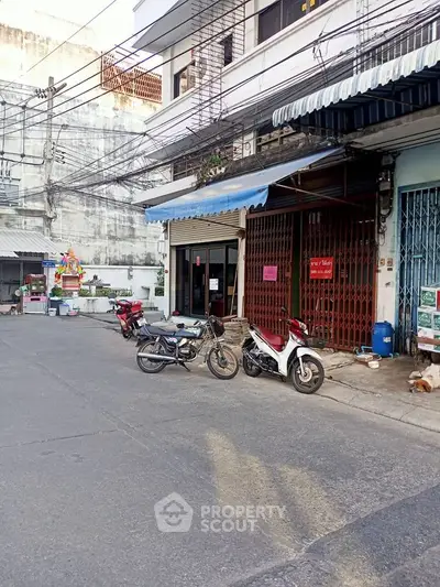 Street view of urban building with motorbikes parked outside, showcasing city living.