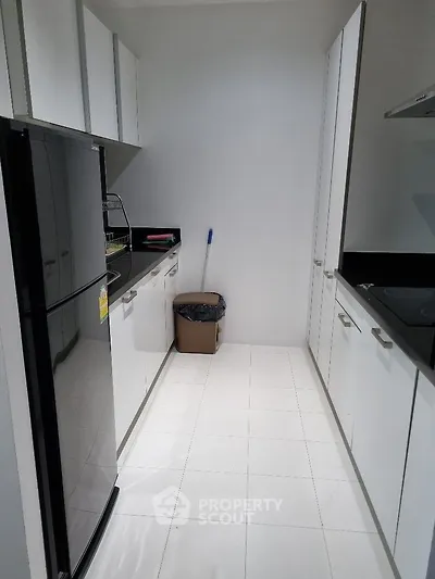 Modern kitchen with sleek white cabinets and black countertops, featuring a spacious layout and contemporary appliances.