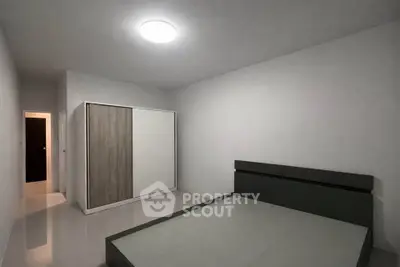 Minimalist bedroom with sleek wardrobe and modern bed frame in a spacious layout.