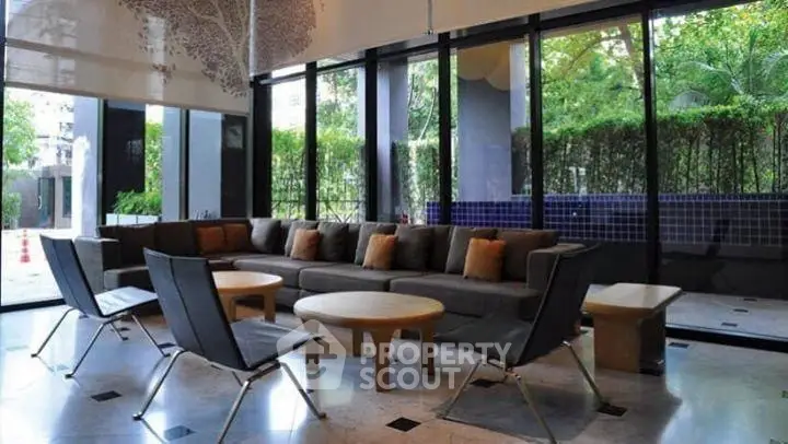 Spacious modern living room with large windows and stylish furniture, offering a serene garden view.