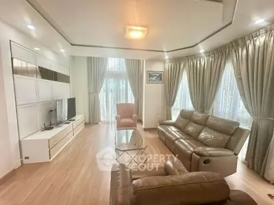 Spacious living room with modern leather sofas and elegant curtains, perfect for relaxation and entertainment.