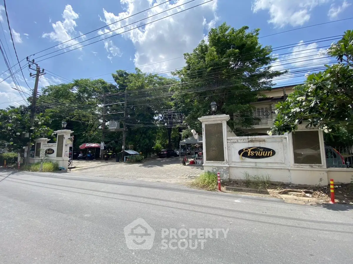 Charming gated entrance with lush greenery and clear blue sky.