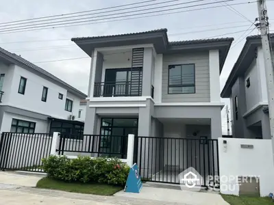 Modern two-story house with sleek design and gated entrance in a suburban neighborhood.