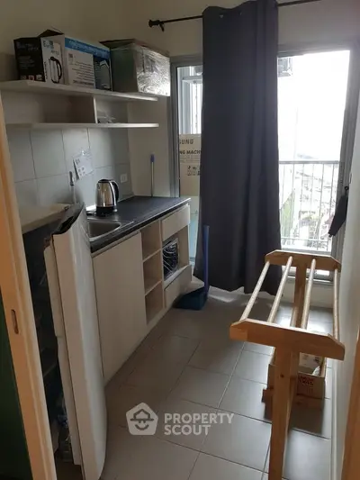 Compact kitchen with balcony access, featuring modern appliances and ample storage space.