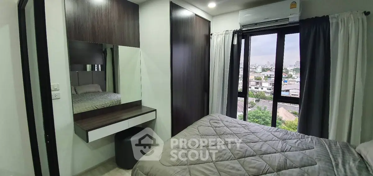 Modern bedroom with city view, featuring sleek furniture and large window for natural light.