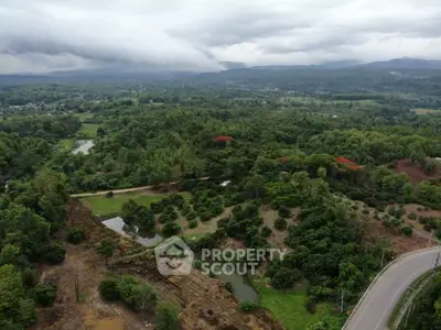 Scenic aerial view of lush green landscape with winding road and distant mountains.