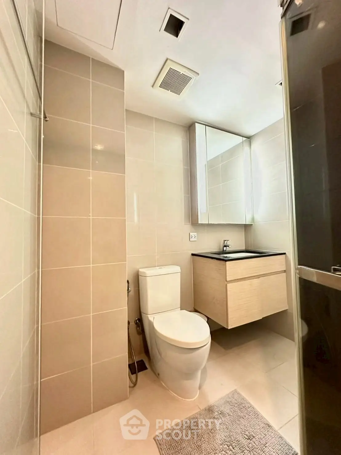 Modern bathroom with sleek fixtures and neutral tiles, featuring a glass shower and vanity mirror.