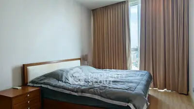 Spacious bedroom with large window offering city views, featuring a cozy bed and elegant curtains.