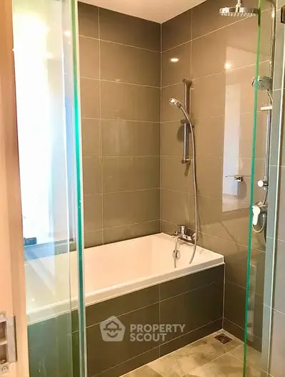 Modern bathroom with glass shower and bathtub in sleek apartment.