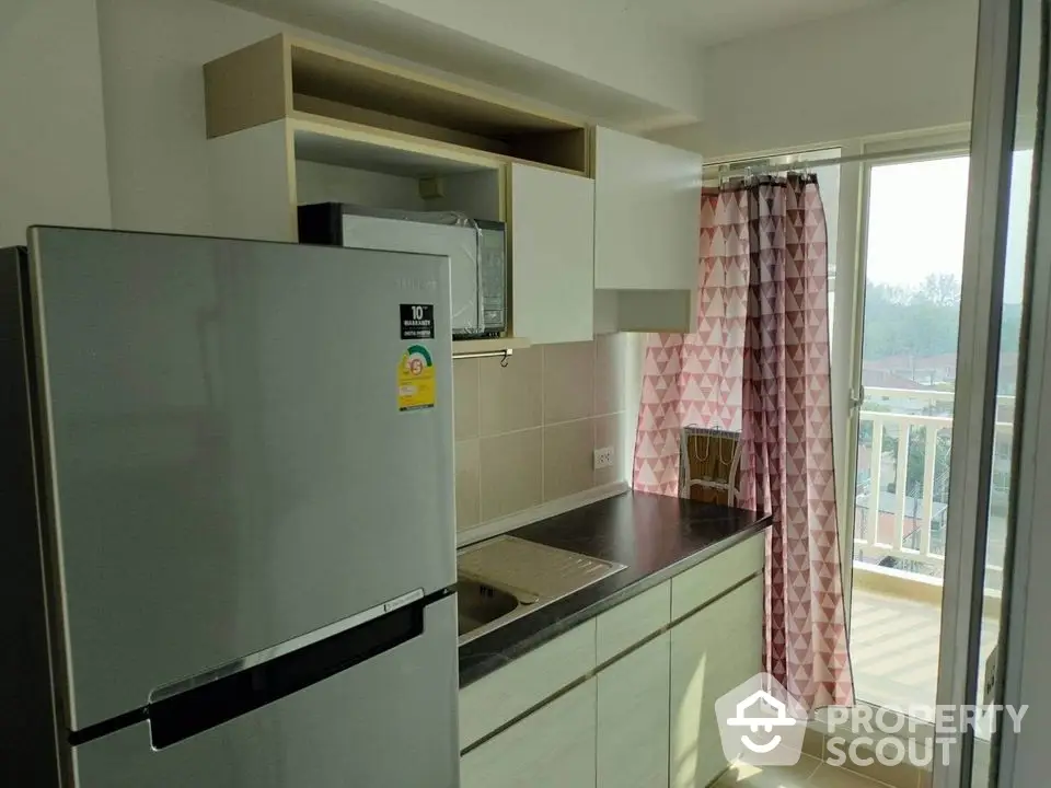 Modern kitchen with balcony view, featuring sleek cabinetry and stainless steel fridge.