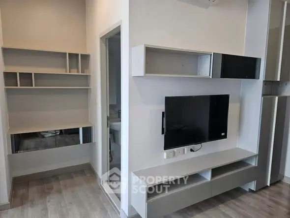 Modern living room with sleek built-in shelves and mounted TV, perfect for contemporary urban living.