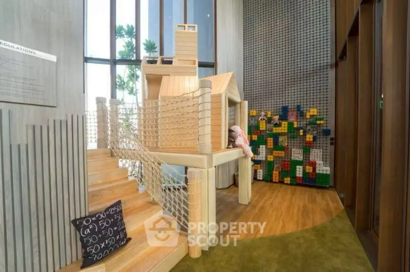Modern indoor play area with wooden playhouse and colorful block wall