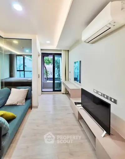 Modern living room with sleek design, featuring a wall-mounted TV, air conditioning, and access to a balcony.