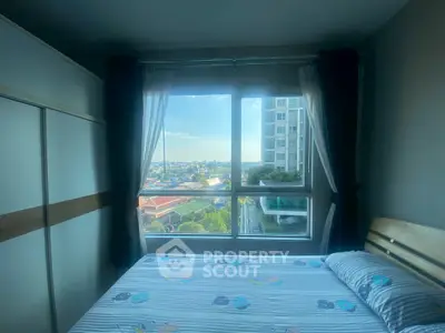 Cozy bedroom with large window offering stunning city view in modern apartment.