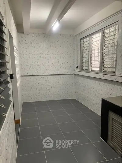 Spacious tiled utility room with large windows and ample natural light.