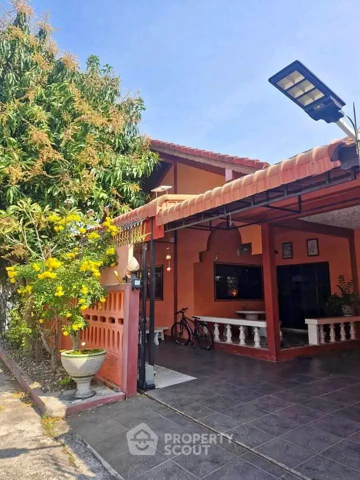 Charming single-story house with tiled patio and lush garden, perfect for outdoor relaxation.