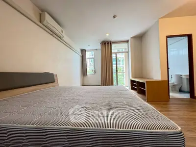 Spacious bedroom with large window and ensuite bathroom in modern apartment