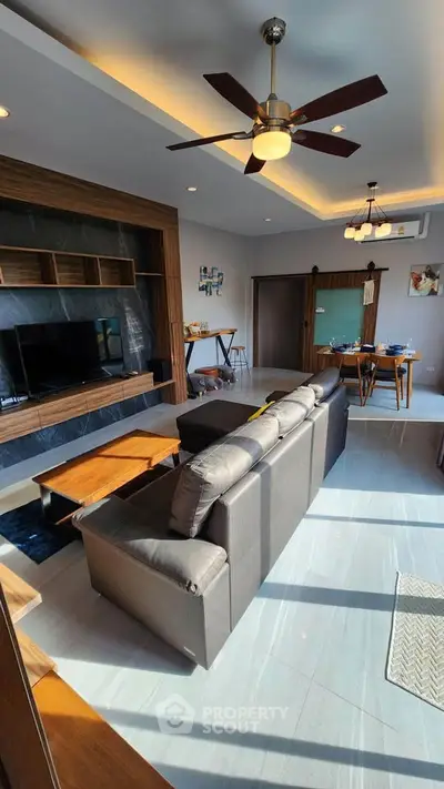 Modern living room with stylish furniture and ceiling fan, perfect for relaxation and entertainment.